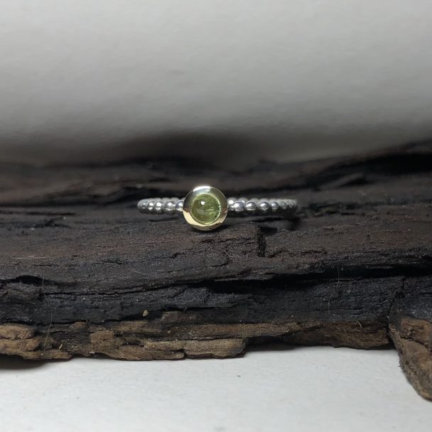 subtiele smalle zilver en gouden ring met ronde bolle groene peridot steen